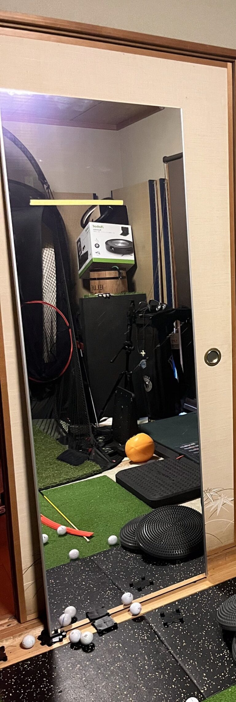 引き戸に立てかけた縦長の割れない鏡。部屋のネットやマットが映り込んでいる