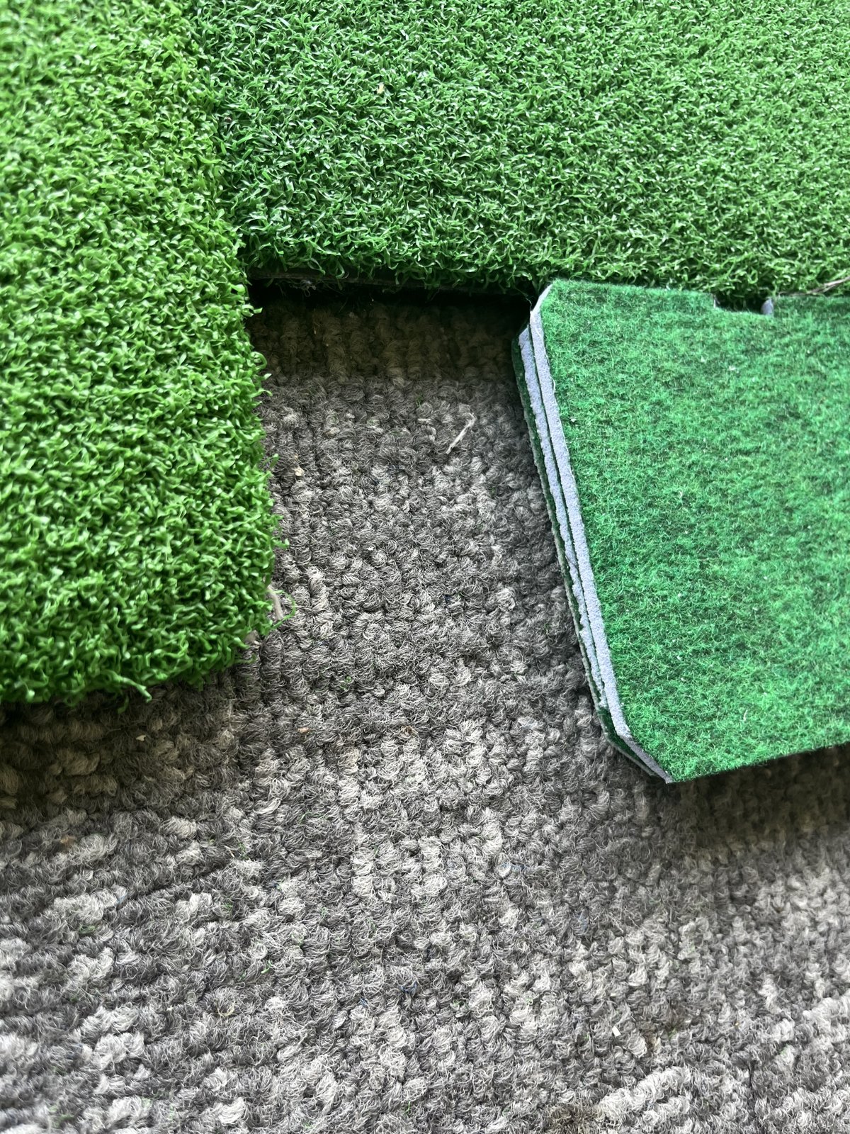 練習場の打席のマットと床の段差に、パターマットを重ねて高さを合わせたところ