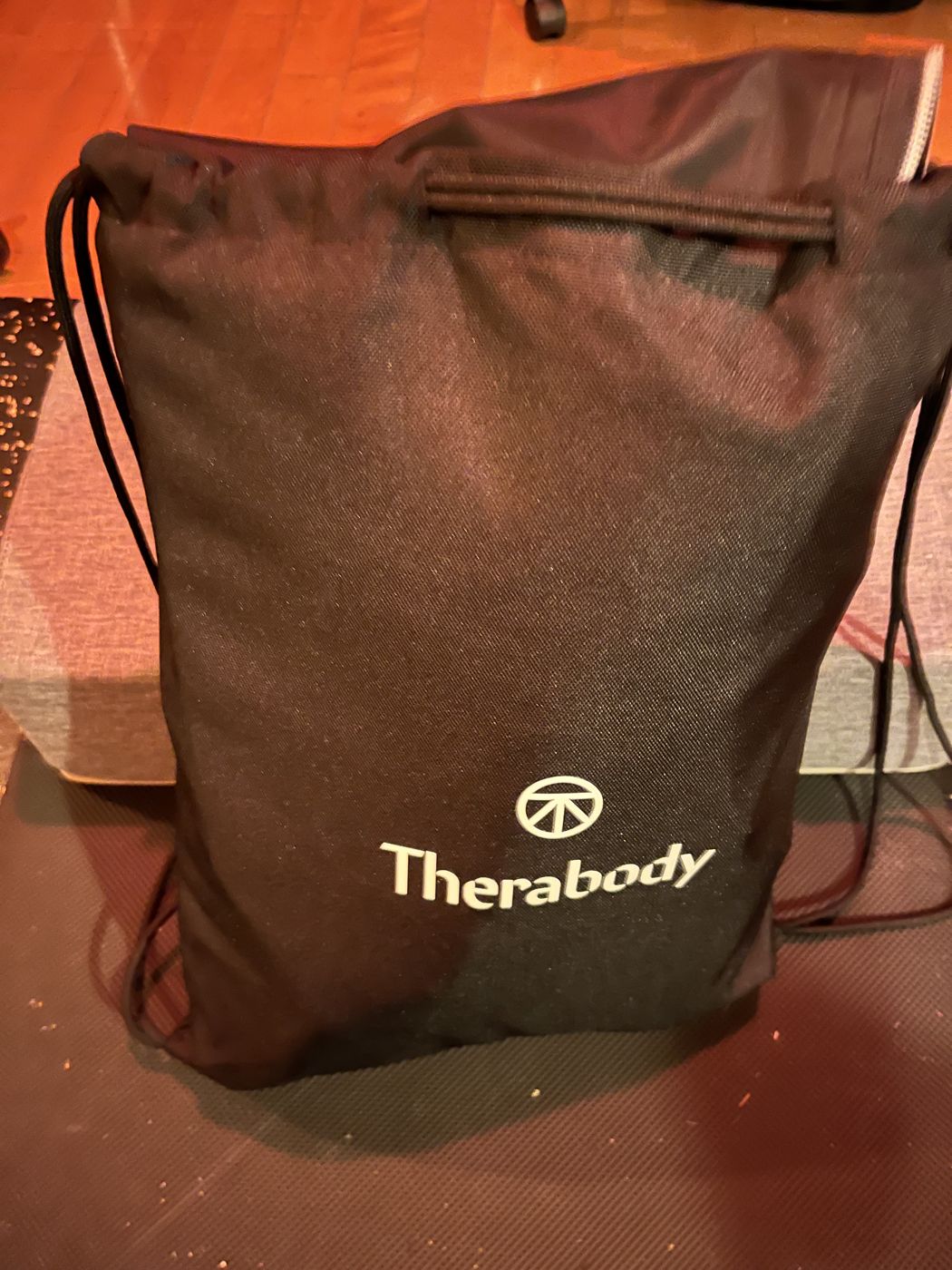 折りたたんだ JetBoots Prime を、Therabody のロゴが入った黒い巾着型の収納バッグに入れた状態。